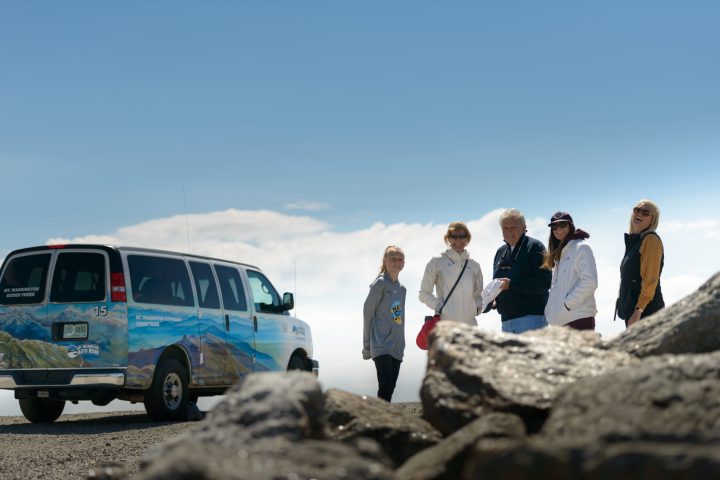 a group of people standing on top of a car
