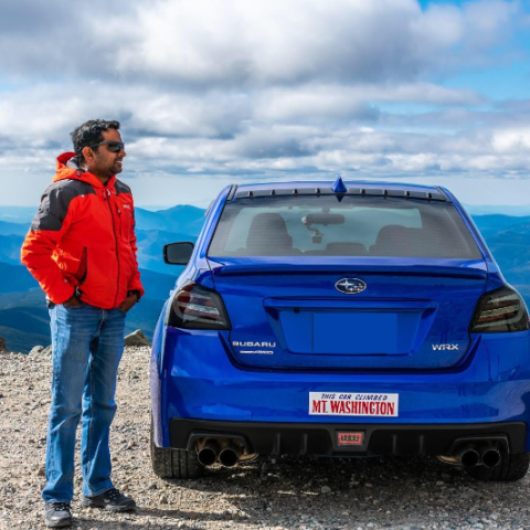 a man standing in front of a blue car
