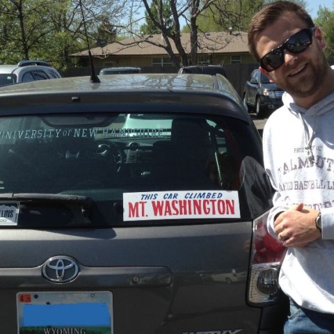 a man standing in front of a car talking on a cell phone