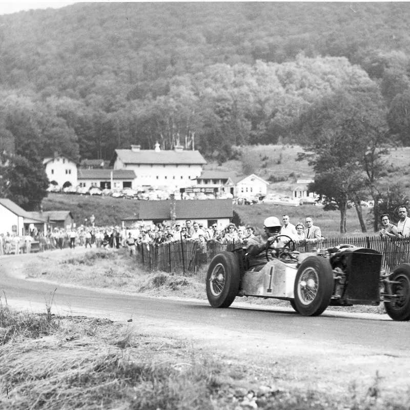 a vintage photo of a truck driving down a dirt road