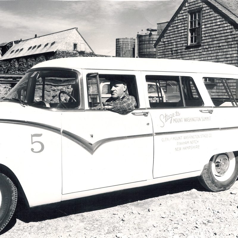 a vintage photo of an old car parked in front of a building