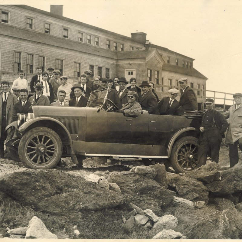a vintage photo of a group of people standing in front of a truck