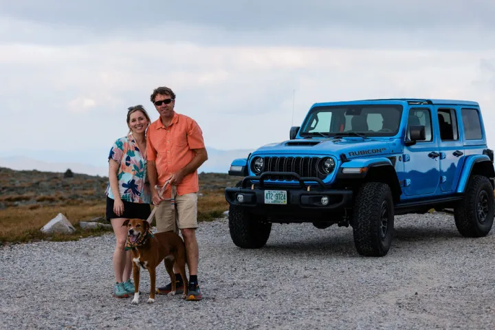 a man and a woman standing in front of a car