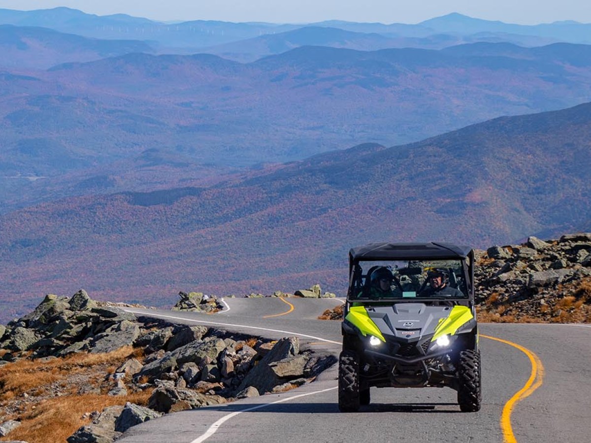 Off-road vehicle driving on mountain road with scenic landscape.